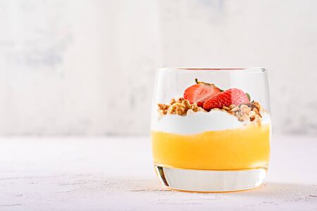 Front view of a glass of vegetarian dessert made of mango smoothie, ricotta, mussels and strawberries with copy spaceの写真素材