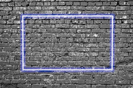 Bright neon blue frame on old dark brick wall texture, grunge backgroundの写真素材