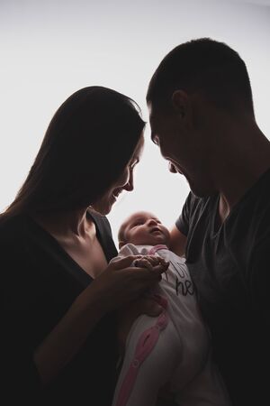 Vertical silhouette family portrait of hugging couple with baby