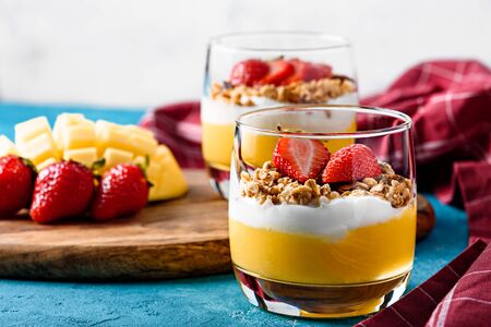 close up of dessert with mango decorated with strawberries with Burgundy napkin on blue backgroundの写真素材