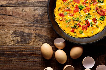 top view rustic healfy Breakfast, scrambled eggs with greens, tomatoes and pumpkin seeds on brown wooden background with copy spaceの写真素材