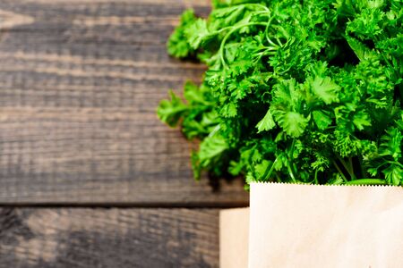 bunch of fresh greens, parsley in an eco-friendly paper bag on wooden background with close-up copy spaceの写真素材