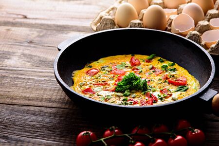 rustic healfy Breakfast, scrambled eggs with greens, tomatoes and pumpkin seeds on brown wooden background with copy spaceの写真素材