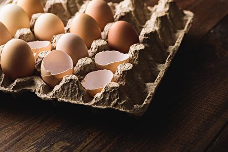 close up eggs with eggshells in eco-friendly cardboard box on brown backgroundの写真素材