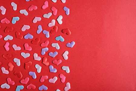 colorful confetti hearts on red background with copy space