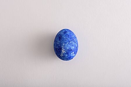 top view single Easter egg in the color of the year-classic blue on white backgroundの写真素材