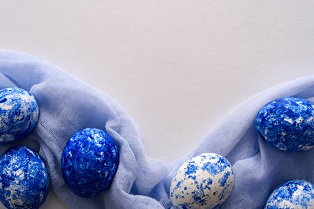 Easter eggs in the color of the year-classic blue with gradient effect on soft blue loth napkin on white background, easter conceptの写真素材