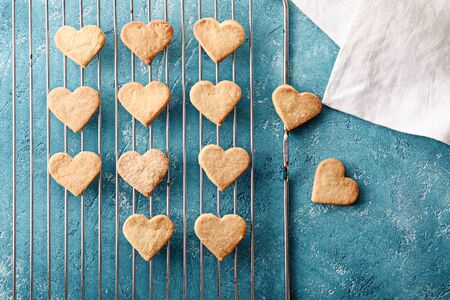 top view of homemade cookies hearts on metal grid on blue background for Valentine's dayの写真素材