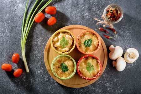 top view of casserole with baked cheese, chicken and mushrooms in multicolored cocoanuts with vegetables on gray backgroundの写真素材
