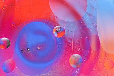colorful bubbles and smears of oil drops on water surface on colored background, art texture