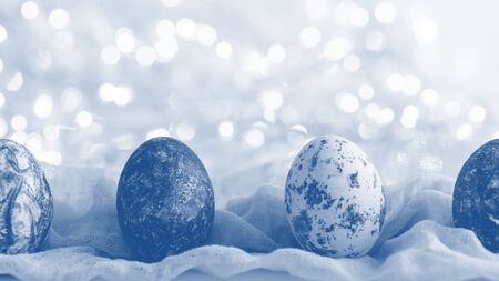 tinted white Easter eggs with pattern and gradient effect in fabric towel on glowing background, happy easter conceptの写真素材