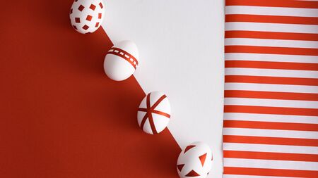four abstract white Easter eggs with red geometric pattern on red and white, striped background, trendy easter conceptの写真素材