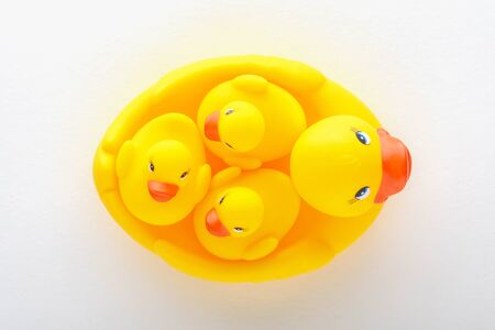 top view of family of yellow toy ducklings on white background, motherhood concept