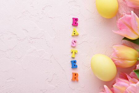 wooden multicolored letters Easter on pink Paschal background with copy space