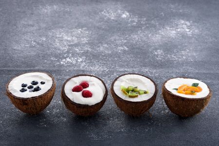 ice cream in coconut bowls with berries in row on gray background, smoothie bowl concept, trendy dessert, copy spaceの写真素材