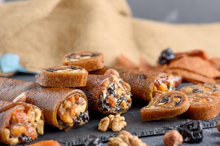 closeup dried apricots, prunes, nuts in Apple roll on gray background, Oriental desserts concept,...