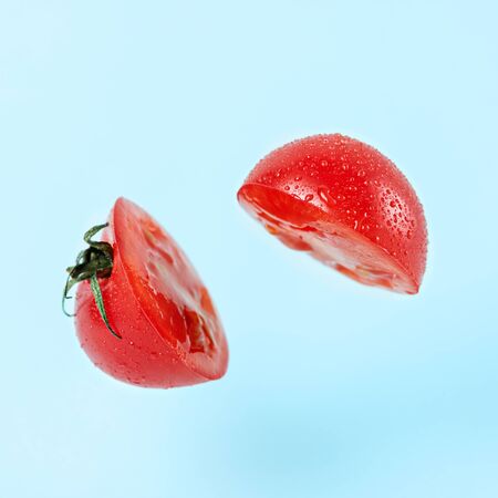 sliced tomato on blue background with levitation effect, art vegetable