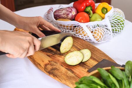 slicing eggplant on wooden Board with knife, cooking vegetarian dinner, closeupの写真素材