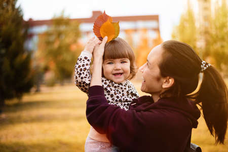 portrait smiling mother and daughter in autumn park, autumn leaves, walking in fresh air, happy childhood, motherhoodの写真素材