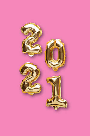 vertical gold foil balloons numbers 2021 on pink background, christmas composition, top view, flat...