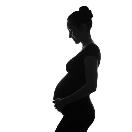 black and white silhouette portrait of pregnant woman with hand on belly, long-awaited pregnancy, ivf pregnancyの写真素材