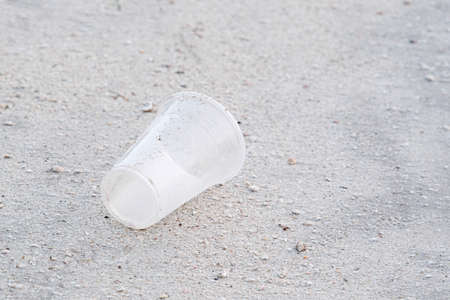 empty plastic disposable glass on beach, environmental pollution, issuesの写真素材