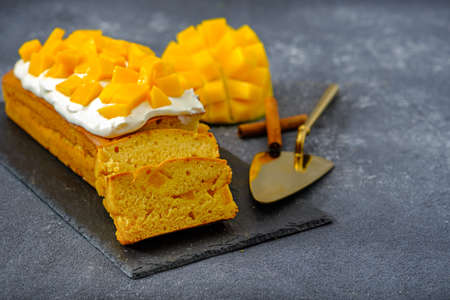mango cake with whipped cream on black stone, closeup, home cooking concept, mango desserts