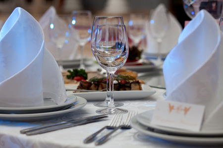 Wine glasses, napkins and salad on the table for the banquet