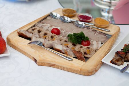 Slices of smoked ham and sausages on a wooden boardの写真素材