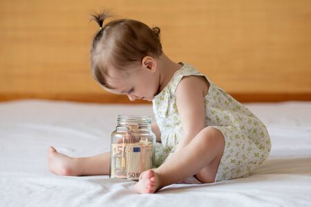 Childrens hands with money in glass jar, close up