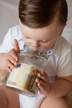 Childrens hands with money in glass jar, close up