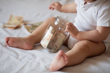 Childrens hands with money in glass jar, close upの写真素材