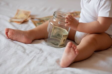 Childrens hands with money in glass jar, close upの写真素材