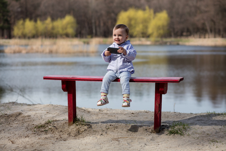 Child playing with smartphone in the park outdoors.の写真素材