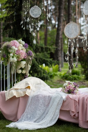 Beautiful wedding bouquet of colorful flowers on a vintage bed on the nature in sunset light, decorations, preparing for the wedding, details, boudoirの写真素材