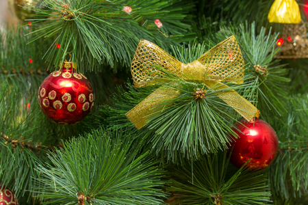 Green Christmas tree in a rich red and gold outfit with glossy glass balls and delicate yellow bowsの写真素材