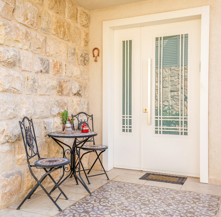 Modern door with glass window, two chairs, table and horse shoe with bell, Israel.のeditorial素材