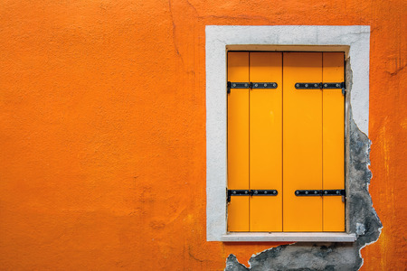 Picturesque windows on yellow wall of houses on the famous island Burano, Venice, Italyの写真素材