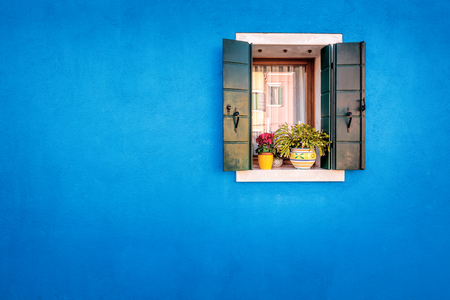 Handsome blue wall with green shutters window of houses on the famous island Burano, Venice, Italyの写真素材