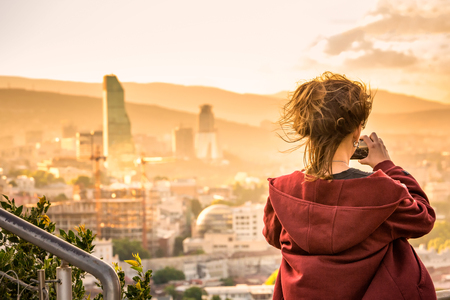 Girl taking photo of areal view at the sunset from high mountain of the TBILISI, GEORGIAの写真素材