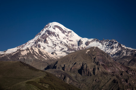 Gergeti Trinity Church also known as Tsminda Sameba on the background of a mountain ridge and...