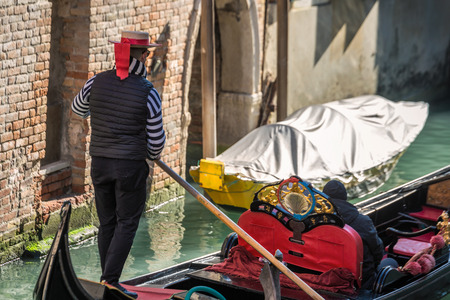 Gondoliere driving red gondola at Venice, Italy.の写真素材