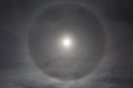 Circle halo in the blue cloudy sky around of the sunの写真素材