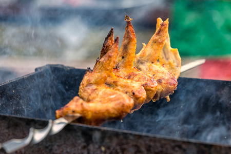 Spicy marinated chicken wings and legs grilling on a summer barbecue with hot flames in a close up view.の写真素材
