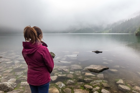 Tourist girl enjoys view on famous lake Morskie Oko in Poland. View from behind.の写真素材