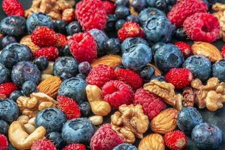 Close up shot of fresh variety of wild berries and nuts, healthy lifestyle.