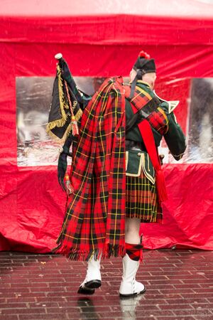 A man dressed in the national costume of Scotland. Men's skirt. On the shoulder of men in a large red checkered scarf. Liverpool. England.の写真素材