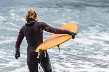 Arctic surfers surfing in Norwegian sea. Unstad, Norwegian village on Lofoten islands. Norwegian sea coastline. Winter water activities sport.の写真素材