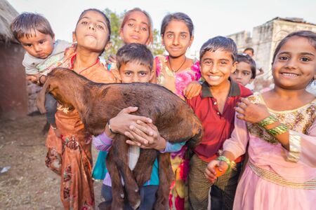 Jodhpur, India - March 08 2017: Happy children sincerely smile and hold a goat in their arms.のeditorial素材
