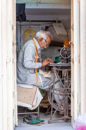 Udaipur, India - March 04 2017: Indian man with glasses sews on an old sewing machine.のeditorial素材